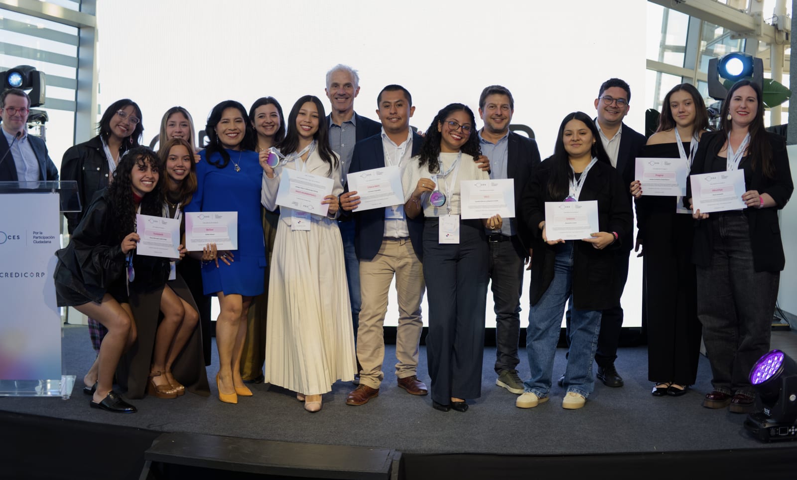 Los equipos ganadores de Voces Credicorp 2025 posan juntos en el escenario, sosteniendo sus diplomas.