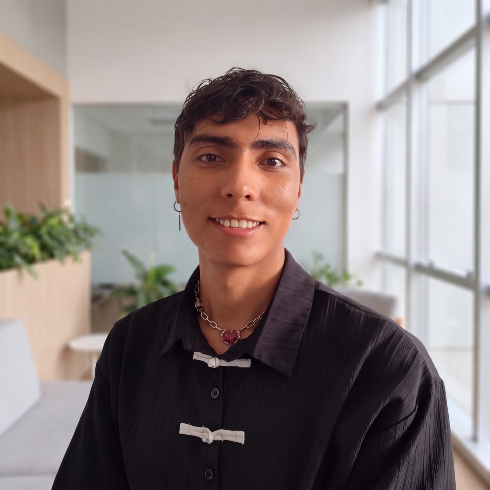 Retrato de Edwin Vesga sonriendo, con camisa negra, en un espacio con ventanales.